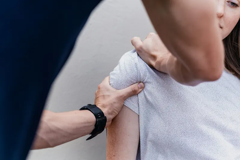 Les mains d'un praticien sur l'épaule d'un patient