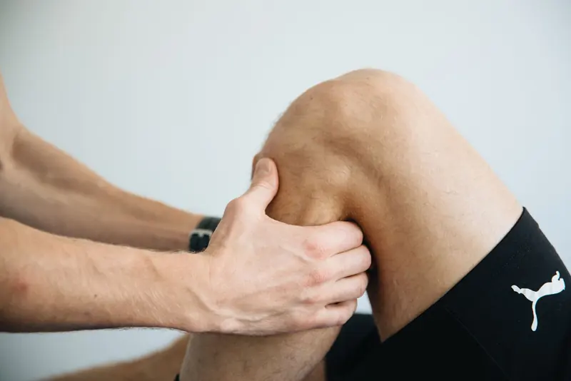 Les mains d'un praticien sur le genou d'un patient