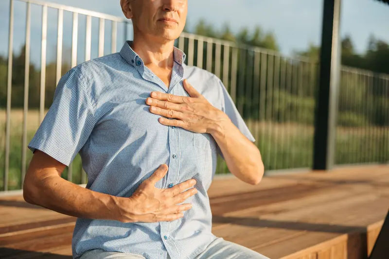 Un homme pose les mains sur sa poitrine et son ventre pour respirer calmement