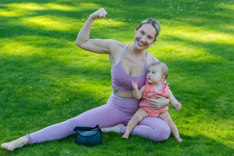 Une mère souriante assise dans l'herbe avec son bébé