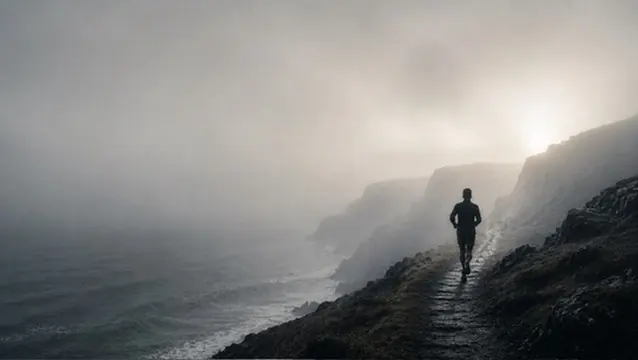 Un coureur sur un sentier en bord de falaise, au-dessus de la mer