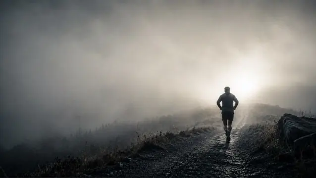 Un coureur sur un chemin de terre, dans la brume du matin