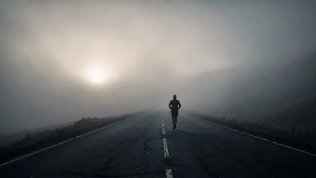 Un coureur seul sur une route dans le brouillard