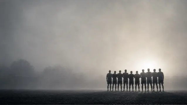Une équipe de football alignée sur le terrain, dans la brume