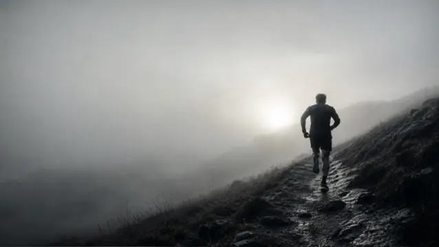 Un coureur sur un sentier de montagne, dans la brume